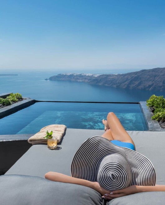 Guest lounging on the terrace sunbed, at Andronis Concept suites with the most epic Caldera view Santorini has to offer. 