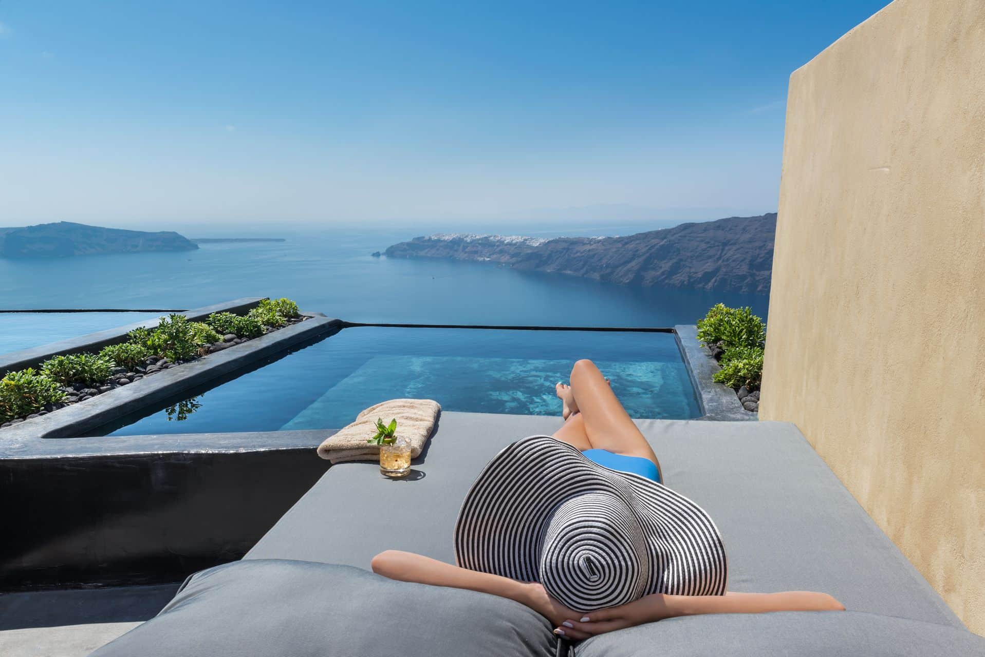 Guest lounging on the terrace sunbed, at Andronis Concept suites with the most epic Caldera view Santorini has to offer. 